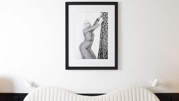 Fotografía en blanco y negro enmarcada de una persona con un vestido estampado colgada en la pared sobre una cama con cabecera acanalada.