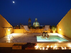 A rooftop terrace with a swimming pool, lounge chairs, and a view of a historic building. - B&B Attico Taranto (Caltagirone)