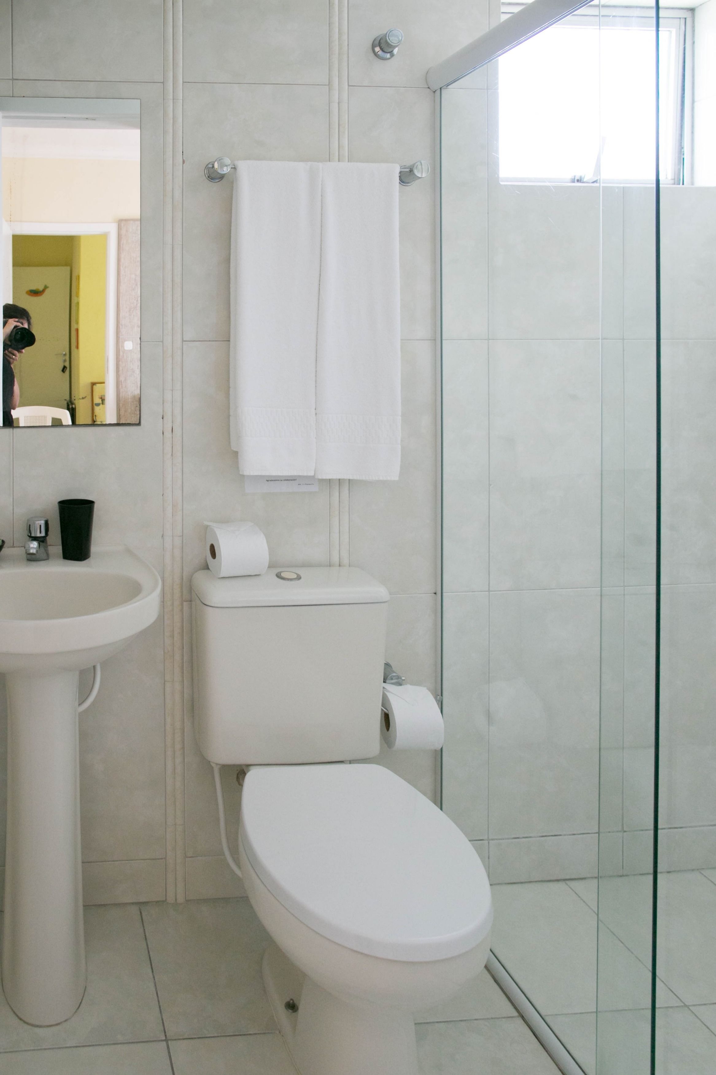 A bathroom with a toilet, sink, and glass shower enclosure.