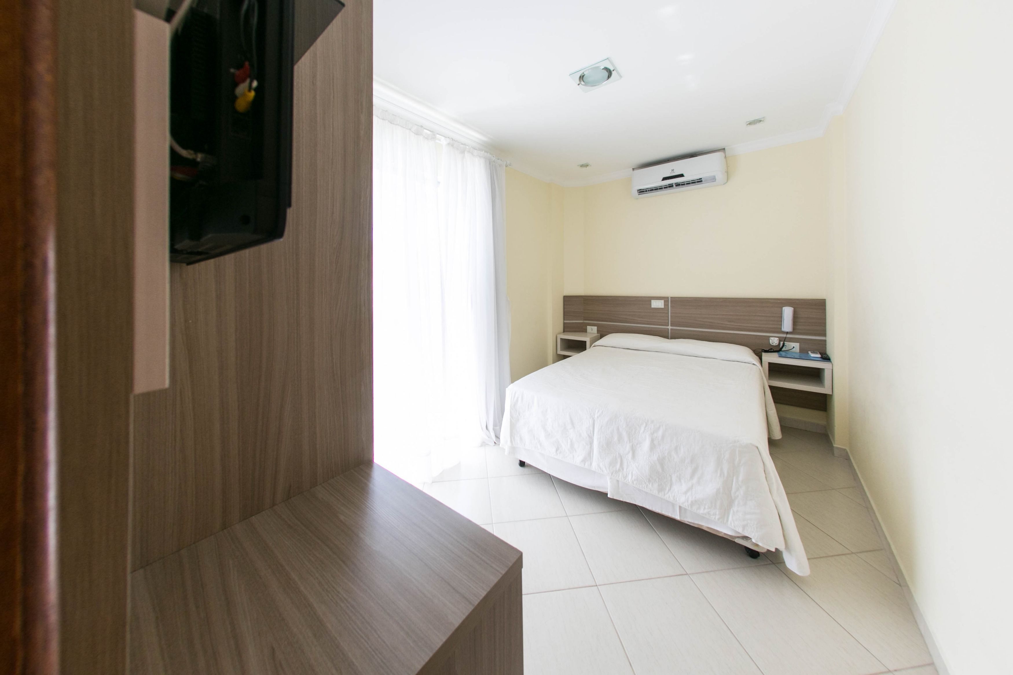 Une chambre d’hôtel équipée d’un lit, d’une table de chevet, d’une commode et d’un appareil de climatisation.