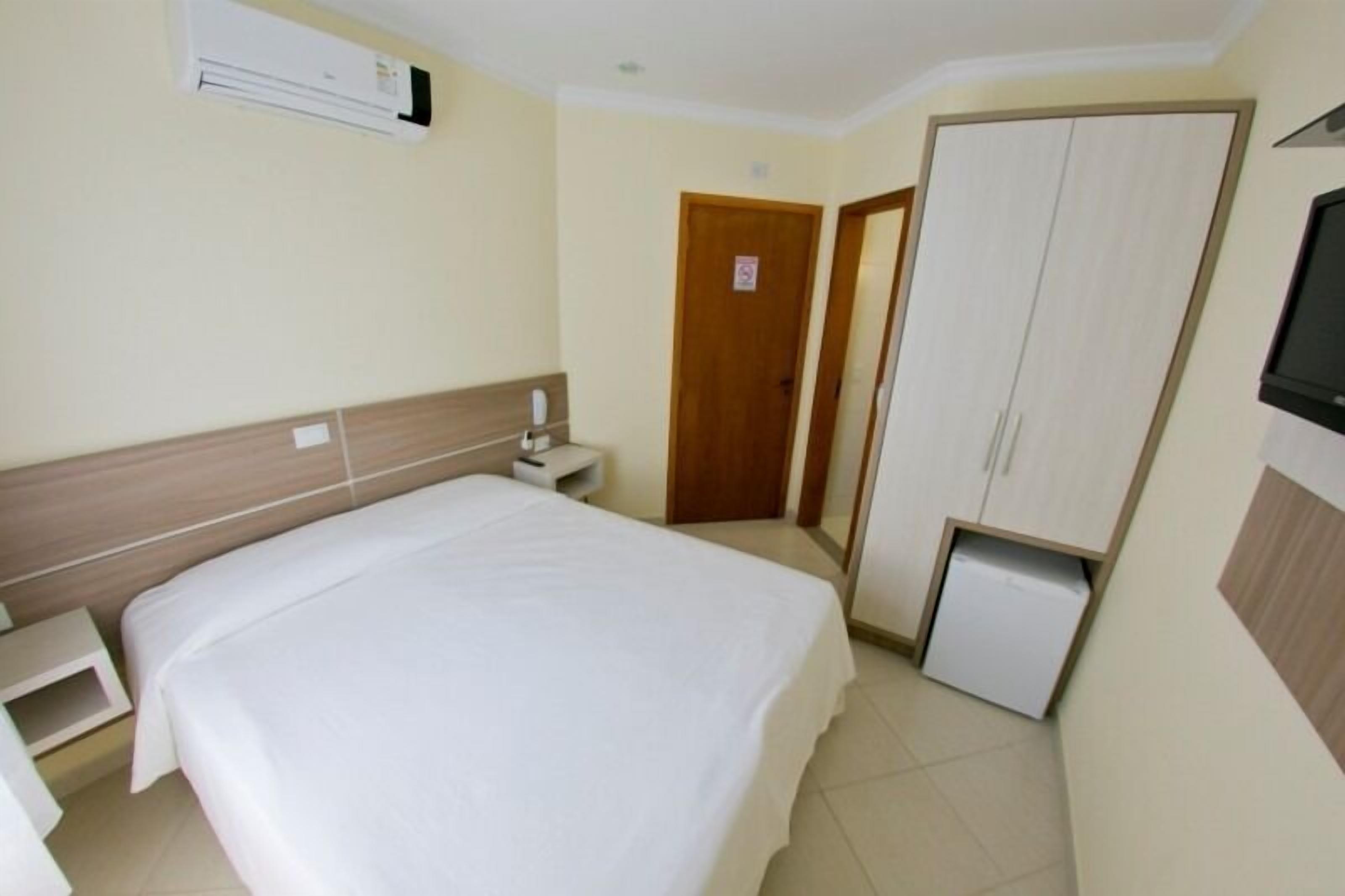 A hotel room with a bed, a bedside table, a wardrobe, and a television.