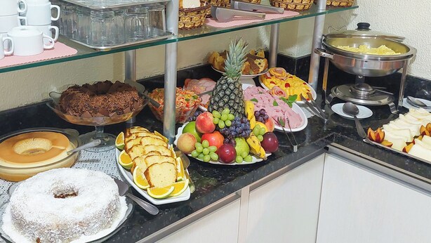 Un buffet con diverse pietanze, tra cui frutta, pasticcini e una torta.