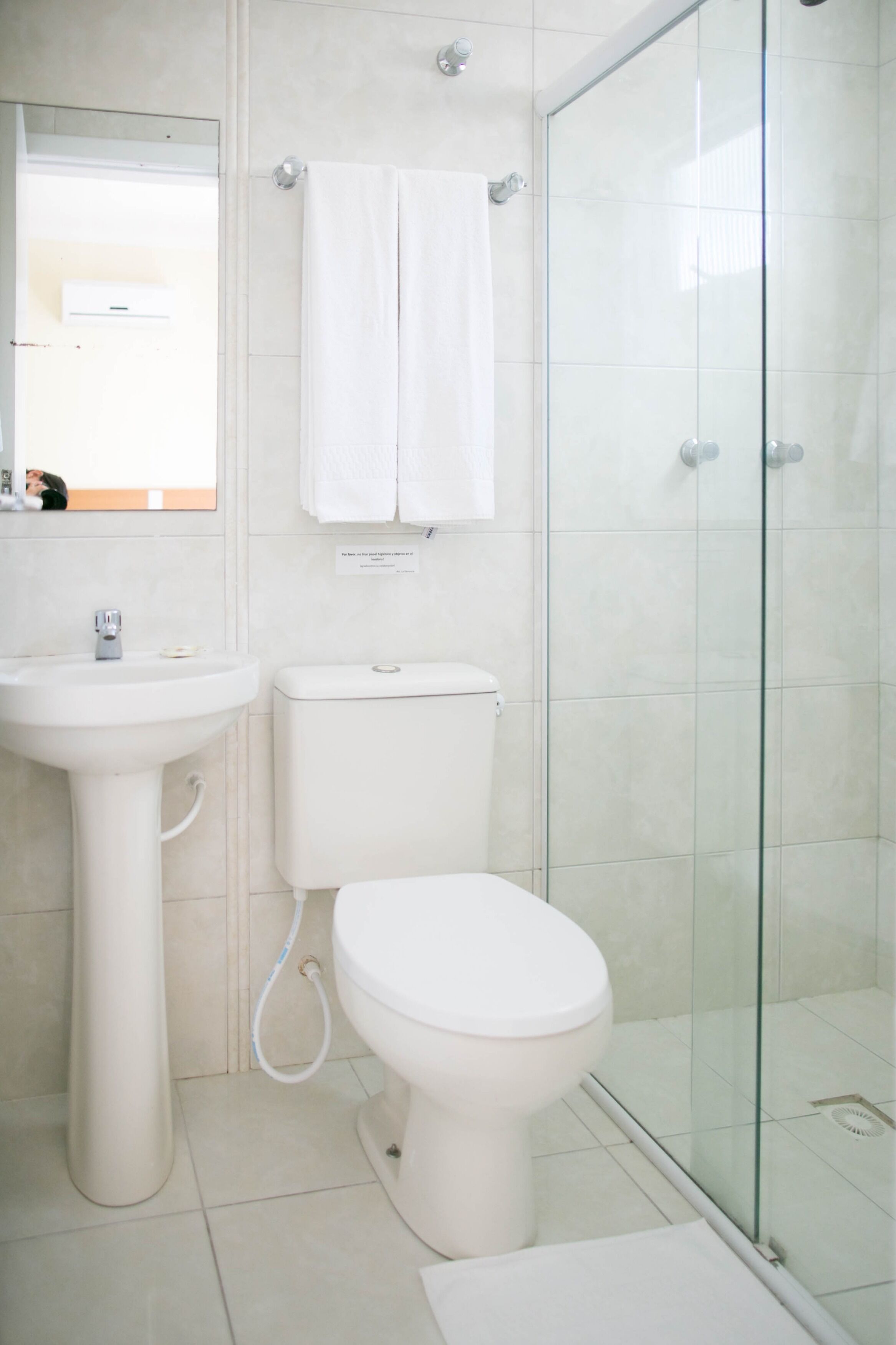 Un baño con lavamanos, inodoro y cabina de ducha de vidrio.