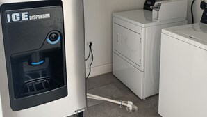 A laundry area with an ice dispenser and a washing machine. - Lotus inn (Houston)