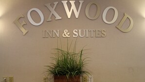 A sign for Foxwood Inn & Suites with a potted plant in front. - Foxwood Inn & Suites (Fox Creek)