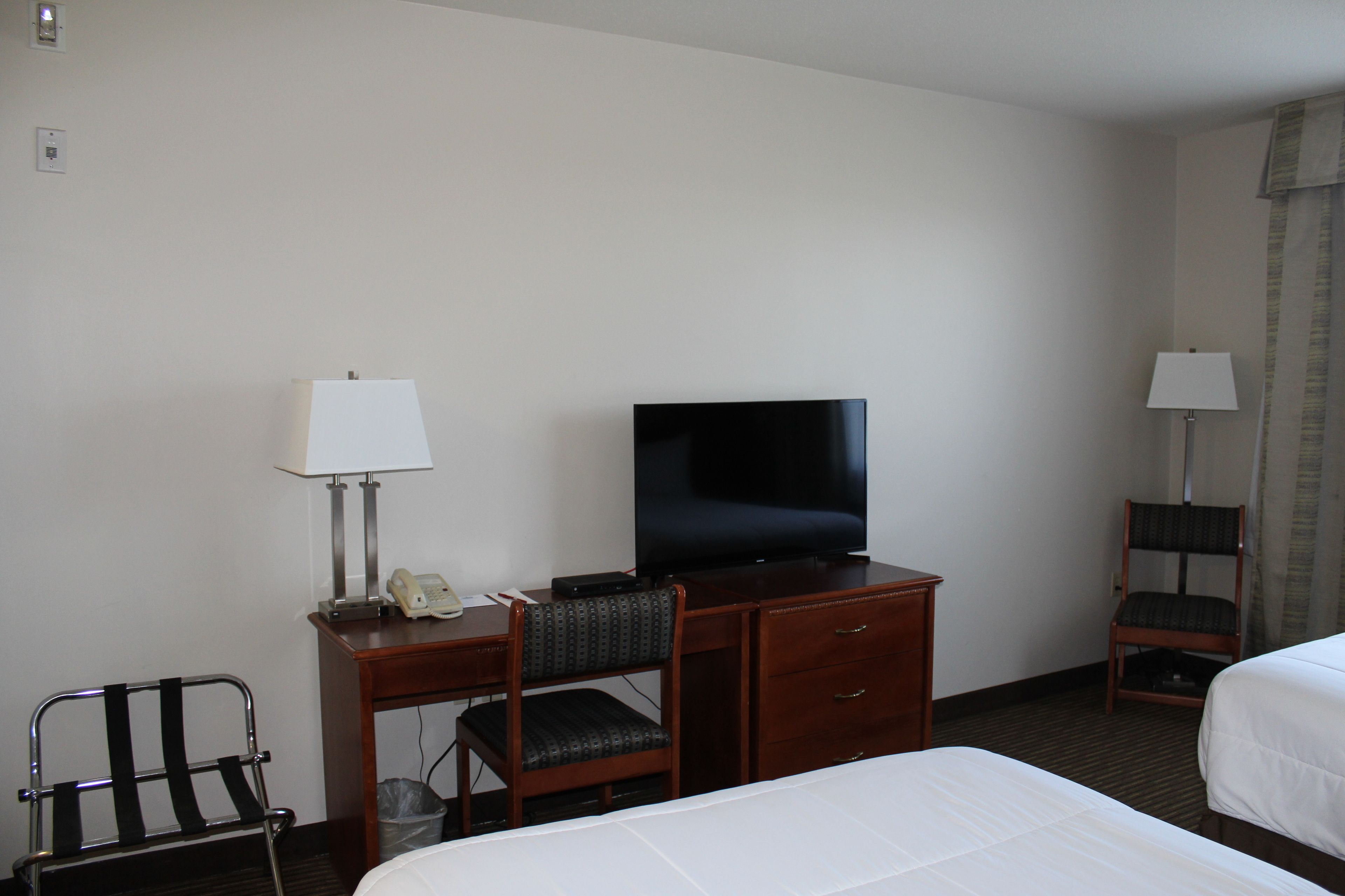Une chambre d’hôtel comprenant un lit, un bureau avec une télévision, une chaise et une lampe.