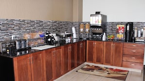 A modern kitchen with a granite countertop, wooden cabinets, a coffee machine, and a tiled backsplash. - Foxwood Inn & Suites (Fox Creek)