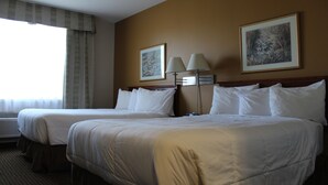 A hotel room with two beds, a large window with curtains, and two wall-mounted lamps. - Foxwood Inn & Suites (Fox Creek)