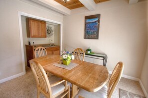 Un comedor con una mesa y sillas de madera, un florero con flores y un cuadro en la pared.