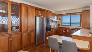 Eine moderne Küche mit Holzausstattung, Edelstahlgeräten und einem großen Fenster mit Meerblick.