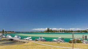 Ein Yachthafen mit vertäuten Booten, einer Brücke und freiem Blick auf das Wasser sowie entfernte Gebäude.