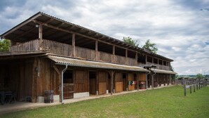A rustic wooden building with a balcony, large doors, and a covered porch area. - - Take a break and reconnect at Farmhouse Kamovci21 - (Kamovci)