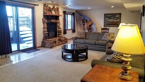 A living room with a stone fireplace, a sofa, a coffee table, and a lamp. - Heated pool-fire pit-central air-near PRNL (Christmas)