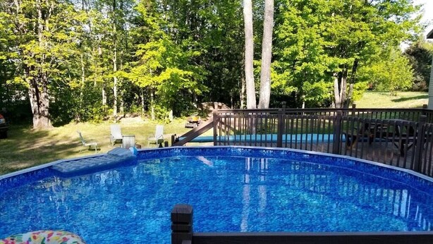 A swimming pool with a wooden deck and lounge chairs. - Heated pool-fire pit-central air-near PRNL (Christmas)