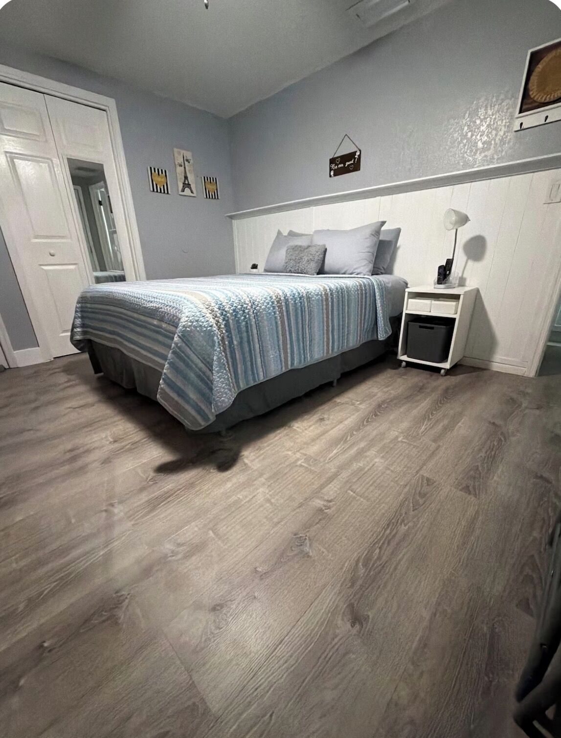 A bedroom with a bed, a nightstand, a wall clock, and a door.