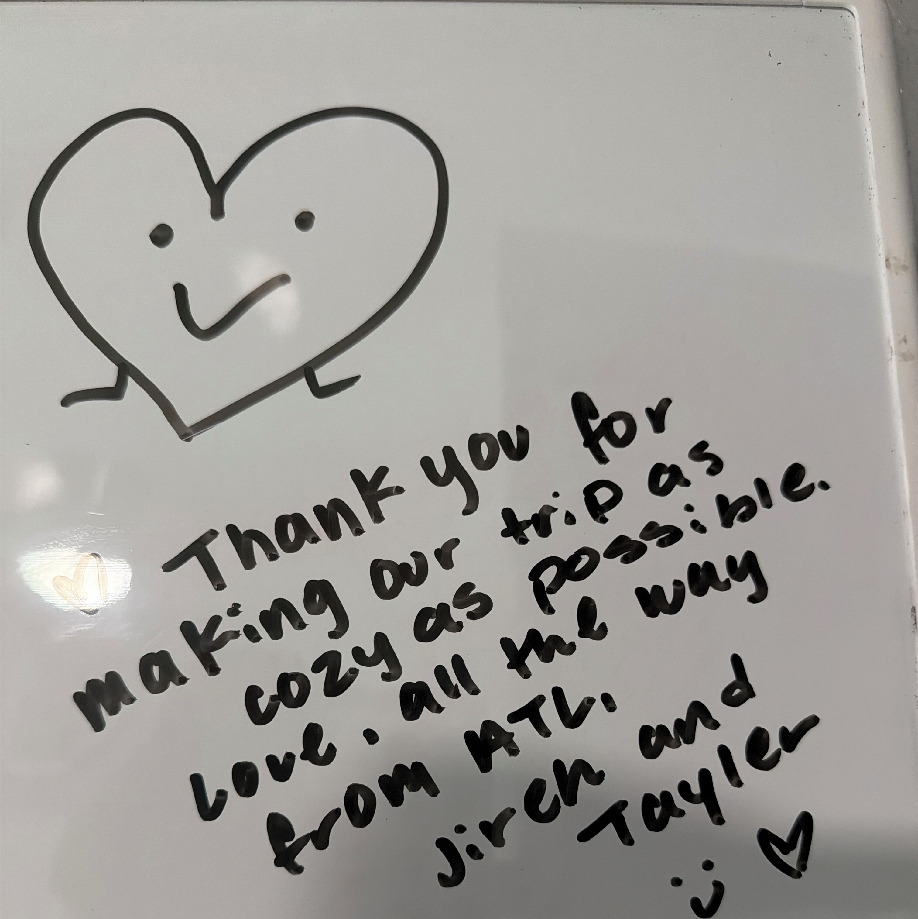 A whiteboard with handwritten notes expressing gratitude for a trip, mentioning a cozy atmosphere, and listing names: Jirch and Taylor.