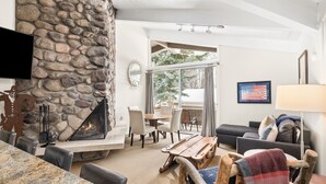 Una sala de estar con chimenea de piedra, televisor de pantalla plana, zona de comedor con sillas y sofá.