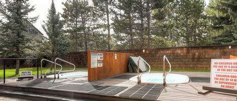 An outdoor hot tub area with wooden steps and metal railings.