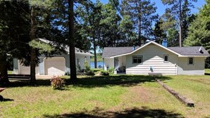 A single-story house with a front porch, a garage, and a small yard with a tree and a bench. - Amazing sunsets/lake views - Near Pictured Rocks (Christmas)