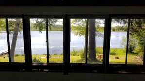 A room with a large window overlooking a lake, a bench, and a picnic table outside. - Amazing sunsets/lake views - Near Pictured Rocks (Christmas)