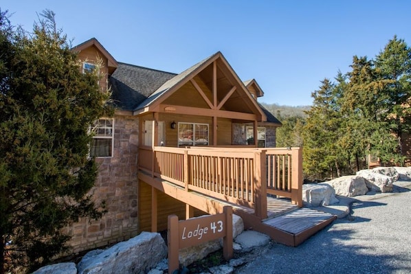 Un chalet doté d’une terrasse en bois et de murs en pierre, portant l’inscription « Chalet n° 43 ».