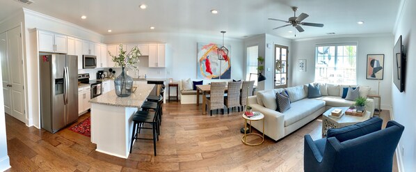 A modern kitchen with stainless steel appliances, a dining area with a large painting, and a living room with a sofa and a ceiling fan. - New, clean, and spacious 3 br/3 .5 ba Oxford condo! (Oxford)