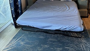 A bedroom with a large bed, a view of the outdoors through a window, and a painting on the wall. - 1-Bedroom Condo Just 1 Block from the Beach and Steps from the Hampton Strip (Hampton)
