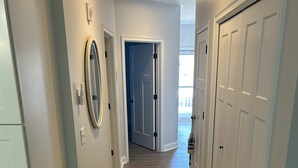 A hallway with a wooden floor, white walls, and a door leading to another room. - 1-Bedroom Condo Just 1 Block from the Beach and Steps from the Hampton Strip (Hampton)