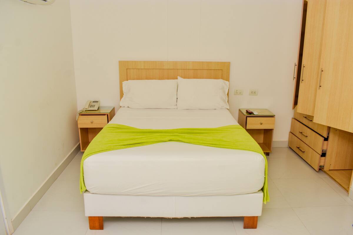 A neatly made bed with a wooden headboard, two bedside tables with lamps, and a wooden wardrobe.