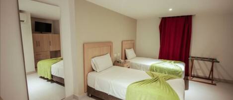 Une chambre d’hôtel avec deux lits, un miroir, une armoire et un rideau rouge.