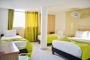 Habitación de hotel con dos camas, un escritorio, una silla, un ventilador y una ventana con cortinas.