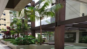 A spacious outdoor area with tiled flooring, planters with various plants, and a covered seating area. - Rosa Branca apartments (Ponta Verde)