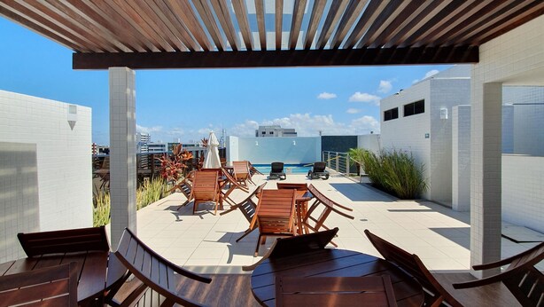 A rooftop patio with wooden furniture, a pool, and a view of the cityscape. - Rosa Branca apartments (Ponta Verde)