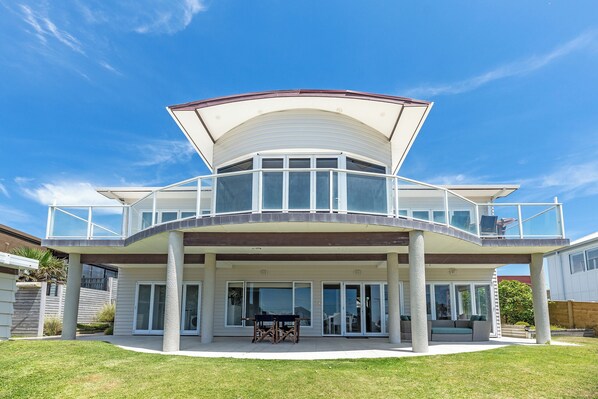 A two-story house with a covered patio, large windows, and a flat roof.