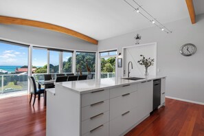 Una cucina moderna con un'isola grande, mobili bianchi e vista sul mare.