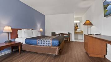 A hotel room with a bed, bedside tables, a desk, and a chair.