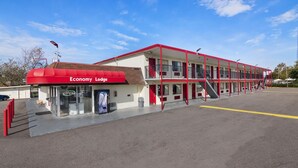 A motel with a red awning, a covered entrance, and a clear sky. - Economy Lodge (Portsmouth)