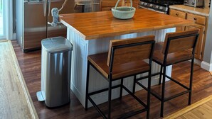 Une cuisine moderne dotée de meubles en bois, d’appareils électroménagers en acier inoxydable et d’un îlot central avec des tabourets de bar.