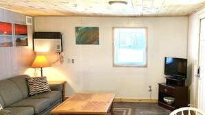 Un soggiorno con soffitto in legno, un divano, un tavolino, una televisione e opere d'arte alle pareti.