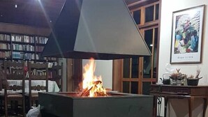 Una habitación con chimenea, un banco, una estantería y un cuadro en la pared.