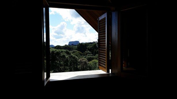 Una habitación con un amplio ventanal que ofrece vistas a un paisaje boscoso y una montaña distante.