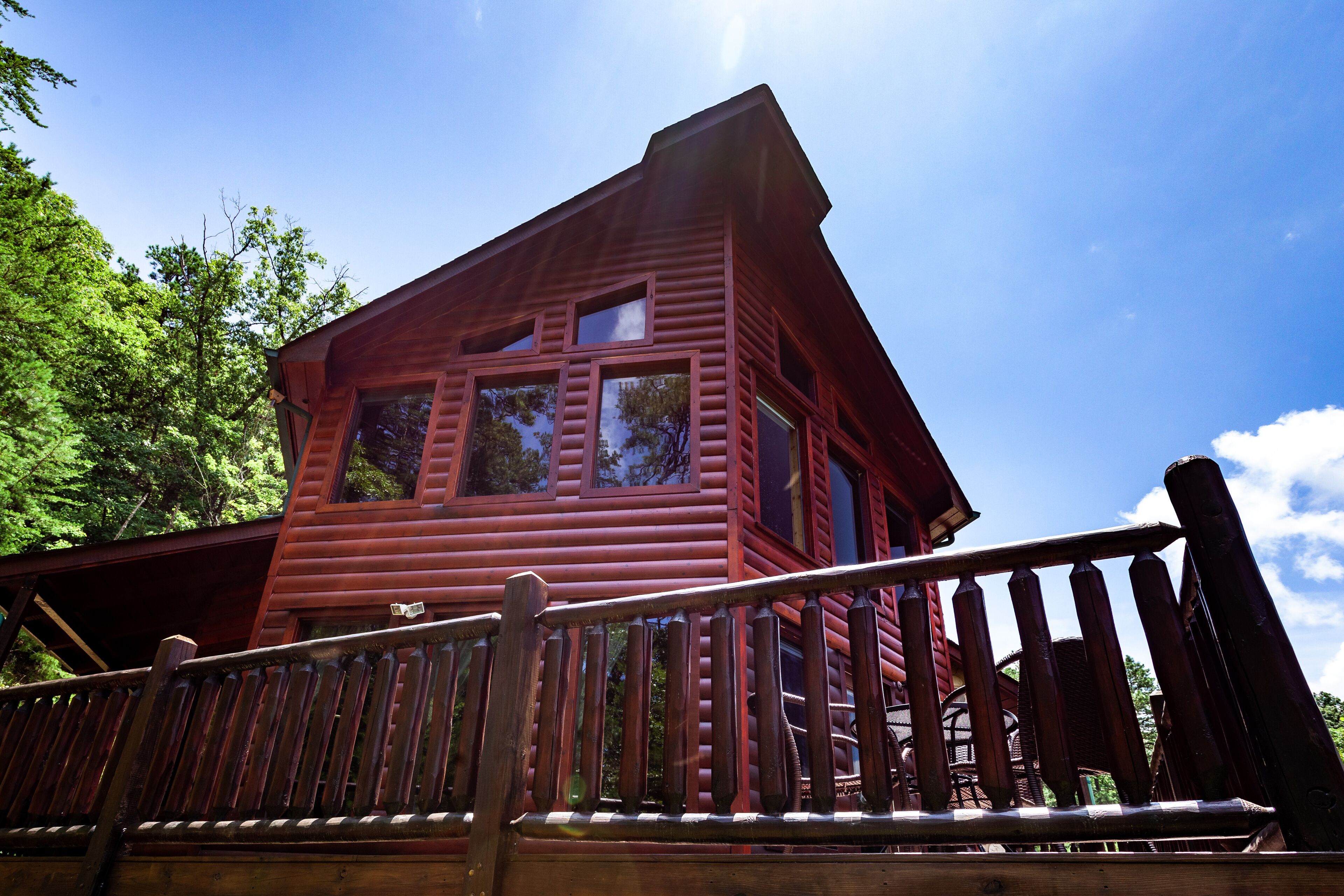 A red wooden cabin with a balcony and a wooden railing.