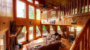 A wooden cabin interior with a cozy living area, a balcony, and a dining space. - 2BR 2BTH PRIVATE, HOT TUB POOL TABLE (Sevierville)