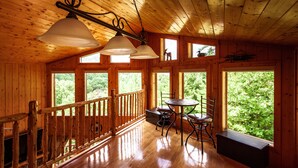 A wooden cabin interior with a dining area, a bench, and a view of the forest through large windows. - 2BR 2BTH PRIVATE, HOT TUB POOL TABLE (Sevierville)