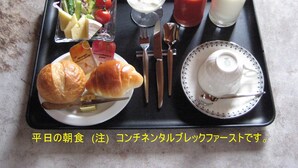 Uma bandeja com itens de café da manhã, incluindo croissants, salada, iogurte, suco de tomate, leite e acompanhamentos.