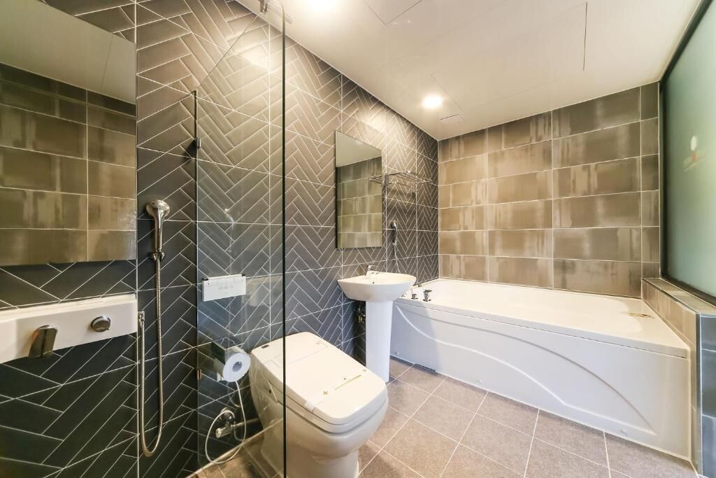A modern bathroom with a glass shower enclosure, a white toilet, a sink, and a freestanding bathtub.