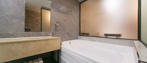 Une salle de bain moderne avec une grande baignoire, un meuble-lavabo avec un miroir et un porte-serviettes.