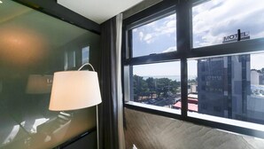 A room with a large window, a lamp, and a view of a cityscape. - Le Idea Hotel (Gyeongju)