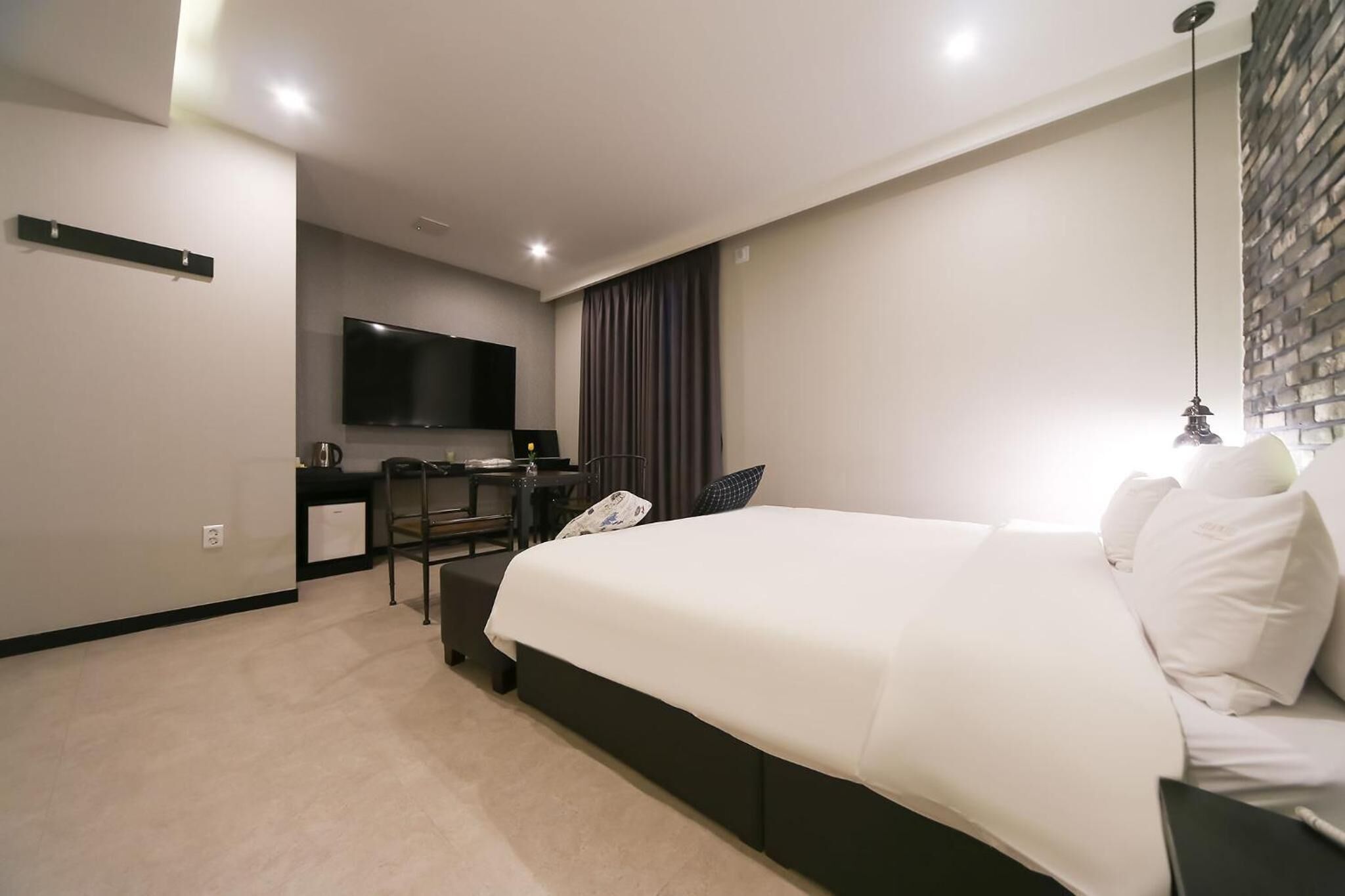 Una habitación de hotel moderna con una cama grande, un escritorio y un televisor de pantalla plana, y una cortina oscura.