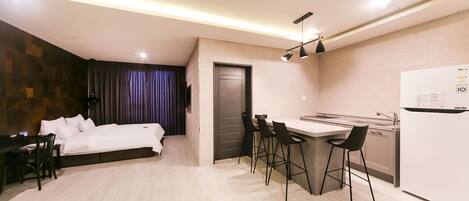Una habitación de hotel moderna con cama, escritorio y kitchenette.